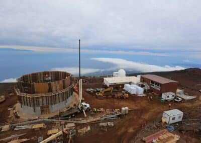 Site construction in February 2014. On the left is the telescope pier formwork installation. In the center of the photo is the utility tunnel transition construction, along with the first four air handling units prepositioned for installation. On the right is the utility building and ice tank slab.