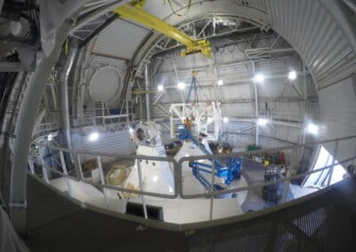 Workers attach the one side of the Telescope Mount Assembly’s Optical Support Structure framework to its precision altitude trunnion. Photo by Heather Marshall, 26 April 2017.