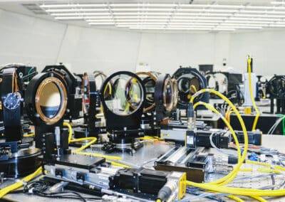 Foreground: In the facility’s instrument laboratory, called the “Coudé Lab”, beam splitters and feed optics channel light into the wavefront correction system, part of the telescope’s adaptive optics infrastructure. The wavefront correction system morphs the shape of the telescope’s “deformable mirror” 2000 times a second in order to counteract turbulence in the Earth’s atmosphere that would otherwise distort the incoming light beam. The wavefront correction system’s fore optics are pictured. More info on the Coudé https://nso.edu/telescopes/dkist/fact-sheets/rotating-instrument-lab/ More on AO: https://nso.edu/telescopes/dkist/fact-sheets/dkist-adaptive-optics/